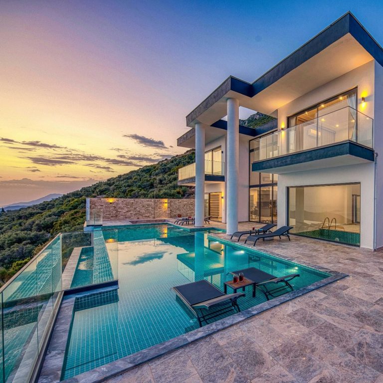 Modern villa with a pool and sunset views over a hillside.